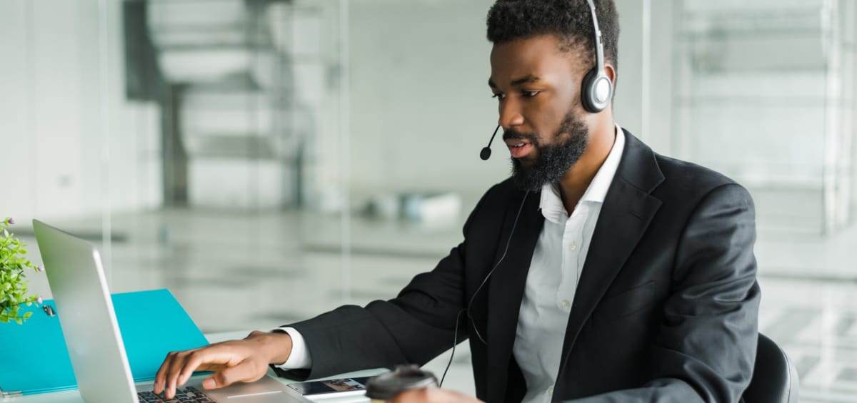 African american man customer support operator with hands-free headset working in the office.